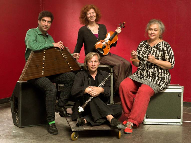 Vier Musiker vor einer roten Wand.